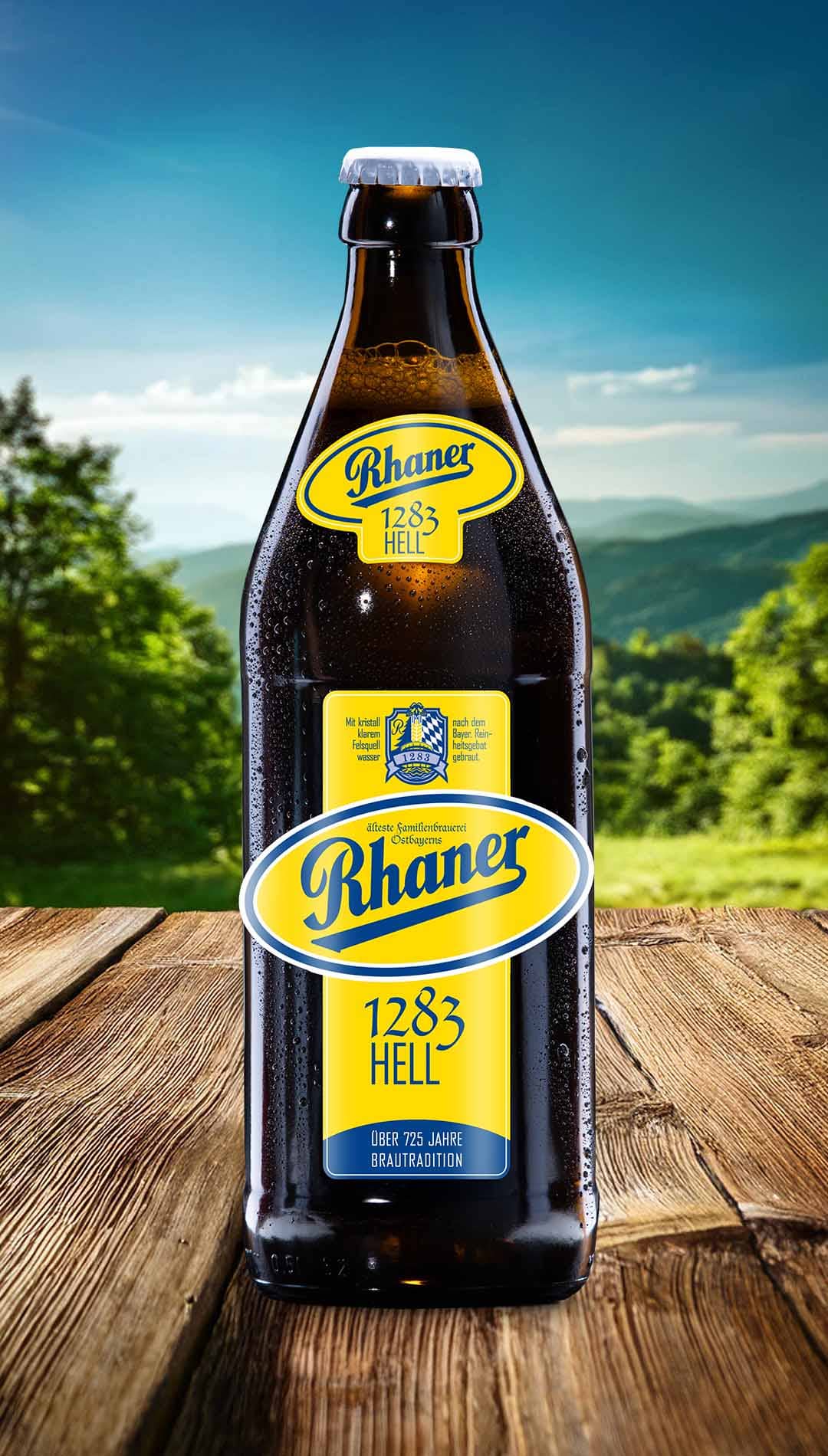 Eine Flasche Rhaner "1904 Pale Märzen" (RPM) Biermanufaktur mit grüner Halsbanderole und einer grafischen Porträt-Illustration einer indigene Person auf dem Etikett auf einem Holztisch vor einer grünen Hügellandschaft