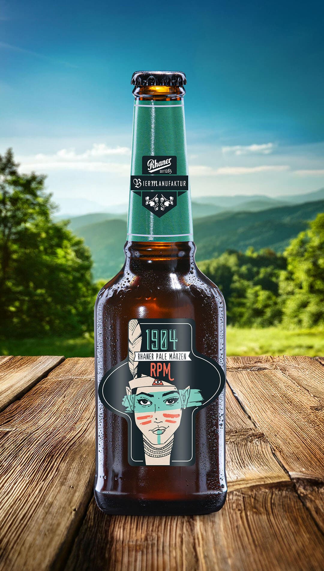 Eine Flasche Rhaner "1904 Pale Märzen" (RPM) Biermanufaktur mit grüner Halsbanderole und einer grafischen Porträt-Illustration einer indigene Person auf dem Etikett auf einem Holztisch vor einer grünen Hügellandschaft