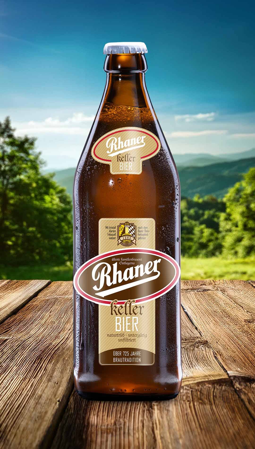 Eine Flasche Rhaner Kellerbier naturtrüb mit braun-beigem Etikett auf einem Holztisch vor einer grünen Hügellandschaft