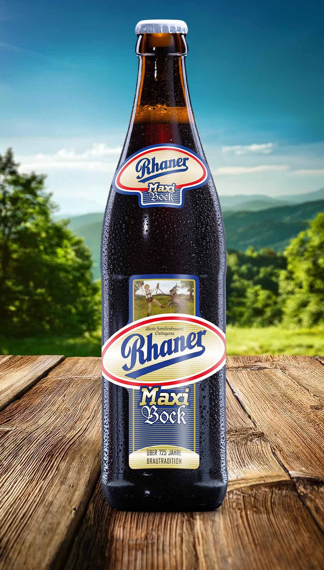 Eine Flasche Rhaner Maxi Bock auf rustikalen Holzplanken vor einem Hintergrund aus grünen Hügeln und blauem Himmel. Das Etikett ist detailliert und zeigt das Rhaner-Logo sowie eine Illustration einer Person, die einen Bock reitet. Die Flasche ist mit Kondenswasser bedeckt.